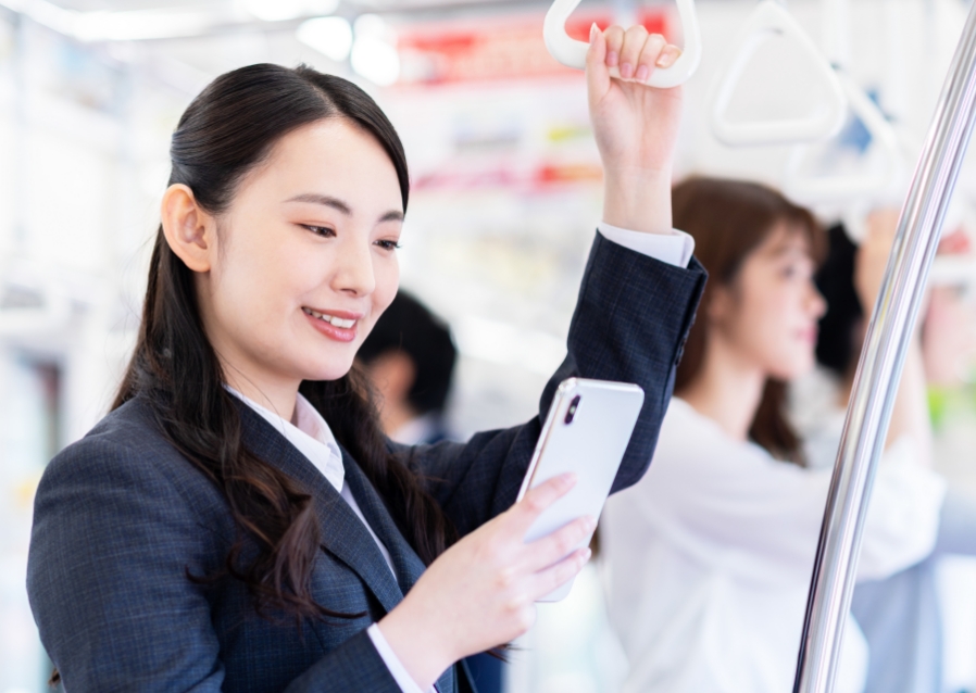 女性が電車の中でスマホを触る写真