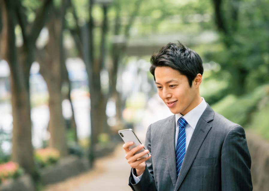 男性が道路でスマホを触っている写真